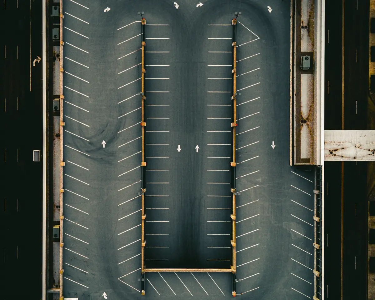 Overhead view of an empty parking lot with marked stalls and directional arrows