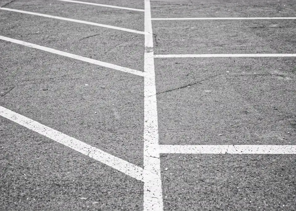 White parking stall lines crossing a textured asphalt surface
